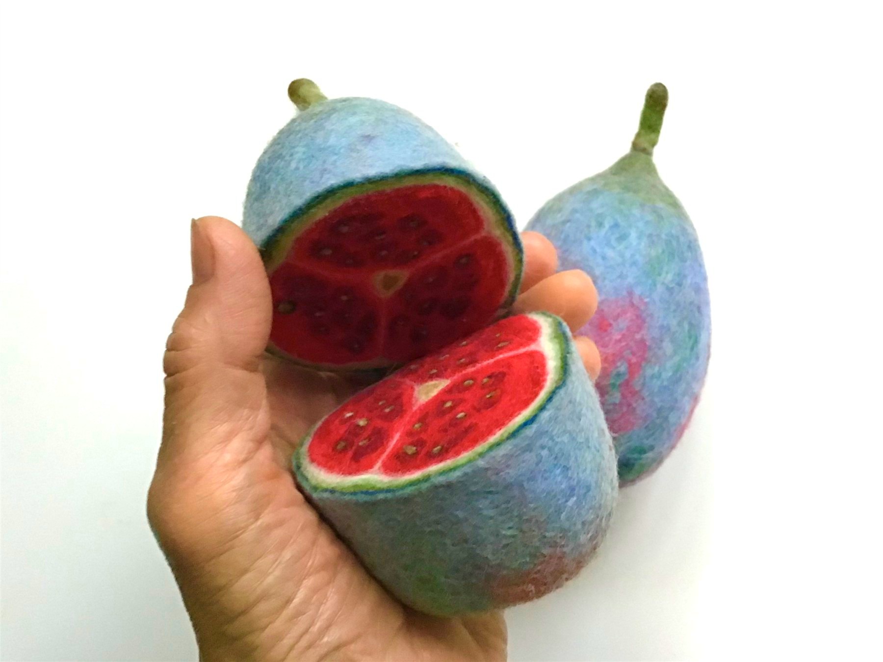 A felted sculpture of the Glaucomelon, blue-skinned fruit sliced open to reveal red flesh