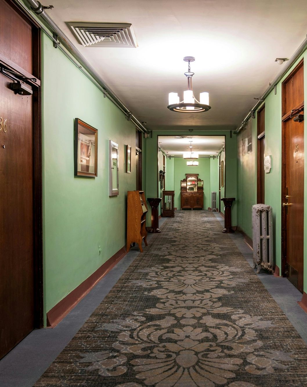 A hallway with doors, a cabinet, and curiosities along the walls