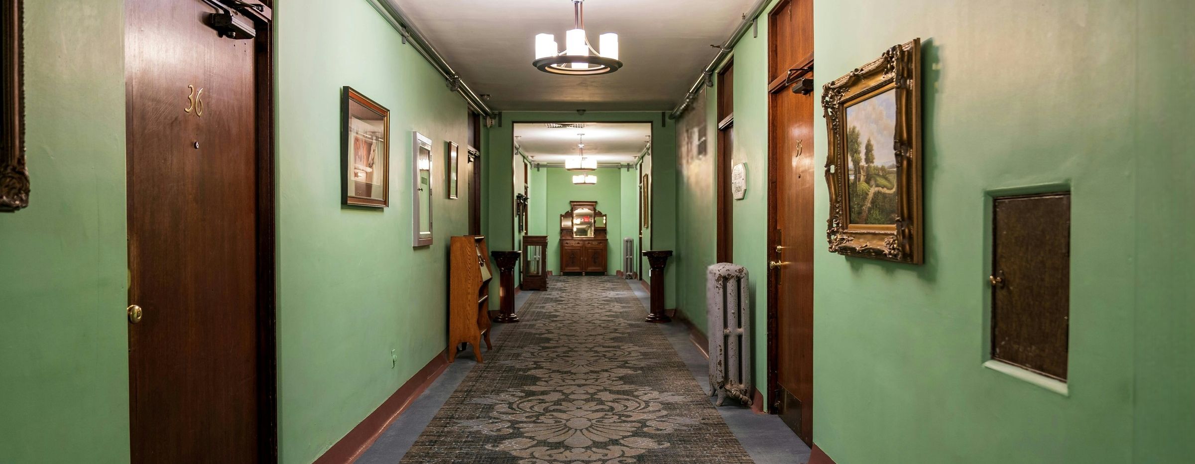 A hallway with doors, a cabinet, and curiosities along the walls